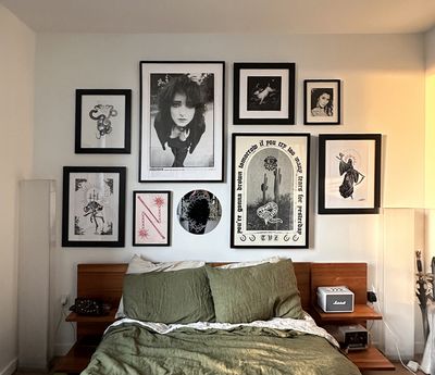 The same gallery wall as in the previous image, this time implemented in a real-life wall over an acacia wood bedframe with olive and natural colored linen bedspread.